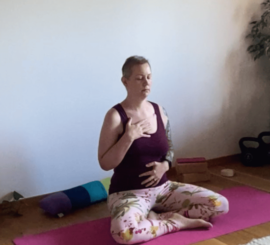 Christine raab sitzt auf einer rosa Yogamatte und zeigt Yogaübungen für schlechte Tage. Atmen, entspannen, Mantra hören.