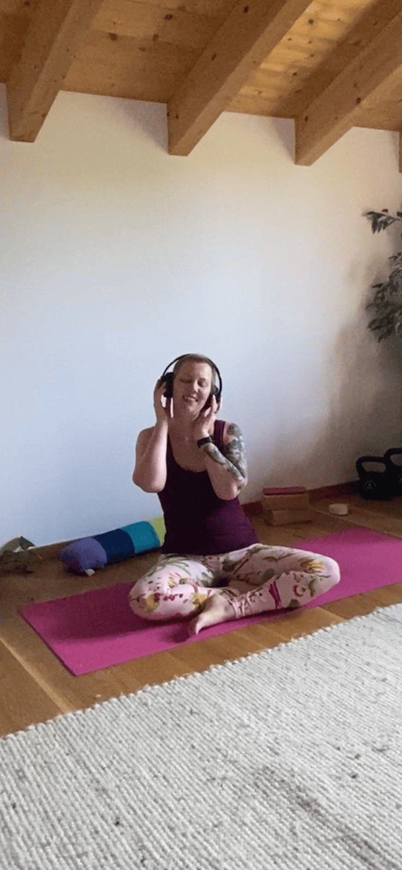 Christine raab sitzt auf einer rosa Yogamatte und zeigt Yogaübungen für schlechte Tage. Atmen, entspannen, Mantra hören.