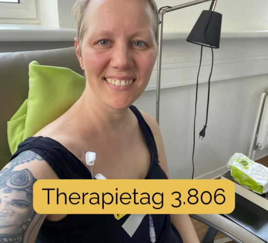 Christine Raab schaut lächelnd in die Kamera. Im Hintergrund sieht man ein medizinisches Zimmer, sie hat eine grüne Decke hinter dem Kopf und eine Portnadel steckt oben neben dem Schlüsselbein. Der Text auf dem Bild sagt: Therapietag 3.806