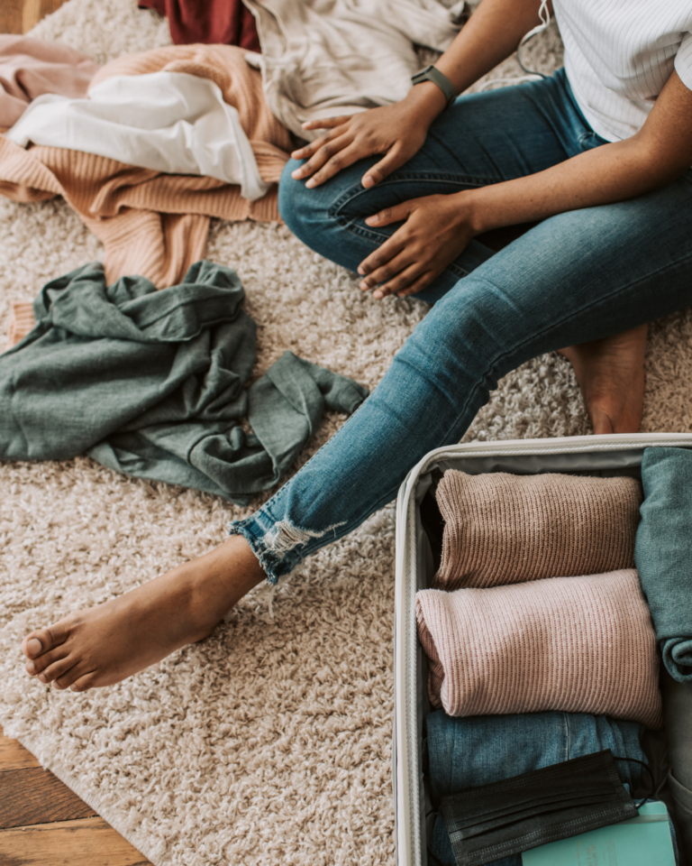 Du siehst eine halb gepackte Tasche bzw. Koffer. Daneben siehst du eine Person sitzen.